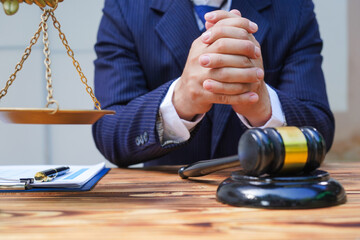 Hands of Asian and African male lawyers working with contract documents and wooden gavel on table...