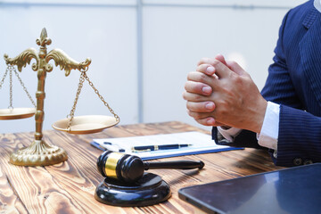 Hands of Asian and African male lawyers working with contract documents and wooden gavel on table in courtroom. Court judges and lawyers