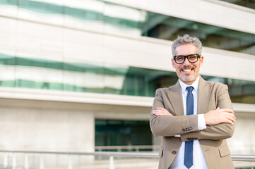 A mature, grey-haired businessman stands with his arms crossed, portraying confidence and a readiness to tackle any challenge. A blend of experience and modern business sophistication.