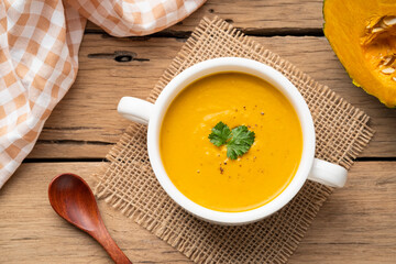 pumpkin carrot cream soup in white bowl,garnished with parsley.Healthy food.Top view