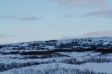 Remote snowy village under pastel sky