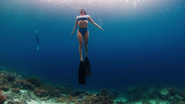 Woman in blue swim suit freedives in the sea