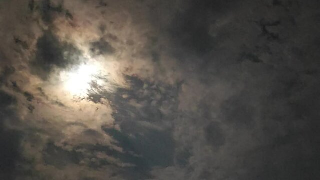 A time-lapse of clouds passing beneath the moon's glow captures the ethereal dance of night, where each moment stretches into a serene, silent ballet of light and shadow.