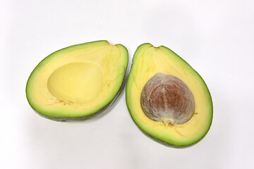 a halved green avocado with a white background