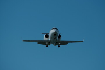 Airplane in the blue sky near the airport. The plane is preparing to land