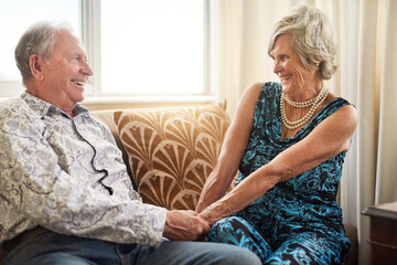 Obraz premium Senior, couple and holding hands at nursing home with love, smile and bonding in living room. Retirement, care and relax in a house happy with wellness on a sofa with marriage and support together