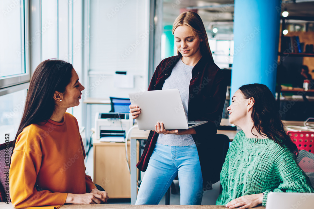 Poster successful three female designers collaborating on developing own fashion company in stylish studio.