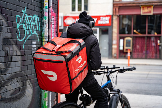 A DoorDash food delivery courier on an bicycle. Toronto, Canada - May 25, 2024.