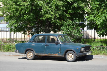 Fototapeta premium An old dark green Soviet car in the courtyard of a residential building, Badaeva Street, St. Petersburg, Russia, May 29, 2024