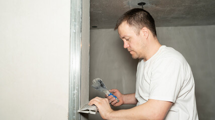 Worker is putting a gypsum plaster on a wall using a spatula. 