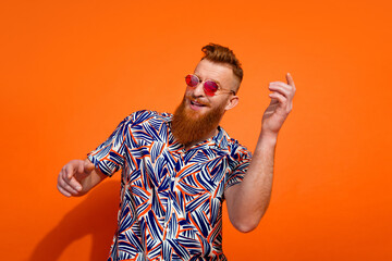Photo of handsome nice guy with red beard in sunglass with mustache dancing at retro party isolated...