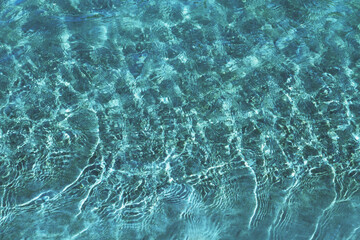 Surface of blue water. In the sunlight. Waves and sun reflection