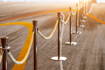 Gold support posts with yellow brown velvet textile fabric rope fencing, access control, vip only