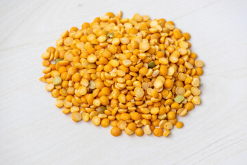 Heap of dry yellow split peas isolated on light wooden background.