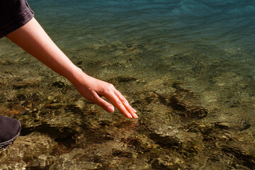 Happy. People in nature. A woman touches the water. A woman's hand on the surface of water, river, sea, ocean.