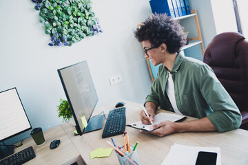 Photo of cheerful handsome agent dressed khaki shirt eyewear writing documents modern gadget...