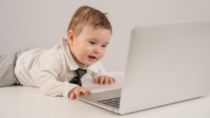 Cute baby boy in a tie working at a laptop. 