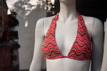 Closeup of orange bra of bikini on mannequin in a fashion store showroom