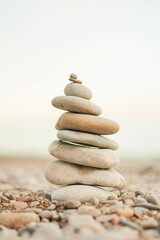 A stack of rocks on a beach. The rocks are of different sizes and are arranged in a pyramid shape. Concept of stability and balance