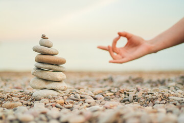 A hand is shown in front of a stack of rocks. The hand is in a yoga pose, and the rocks are...