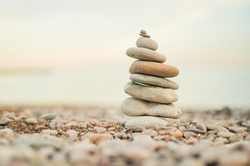 A stack of rocks on a beach. The rocks are of different sizes and are piled on top of each other. The scene is peaceful and serene, with the ocean in the background