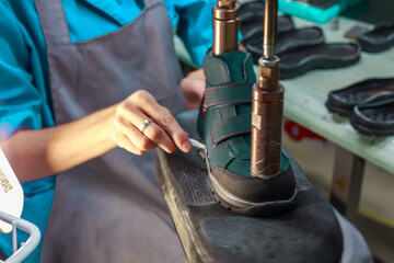 A shoe factory worker is gluing the sole of a shoe.