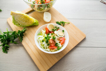 fresh vegetable salad, cabbage, tomatoes in a bowl on a wooden table