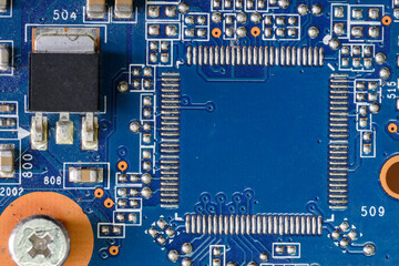 A fragment of a blue computer board with capacitors and desoldering for a microprocessor