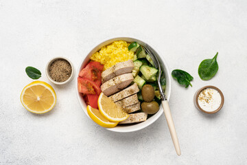 Healthy salad with chicken, tomato, cucumber, olives and rice in bowl on white background with copy space