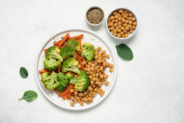 Healthy food broccoli, carrots and chickpeas on a plate top view on a white background with copy space