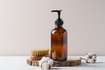 Liquid soap or lotion in glass jar container on wooden podium surrounded by cotton buds. Natural cosmetics concept
