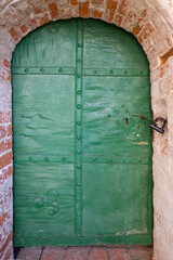 An old medieval green metal door with forged reinforcement elements and a lock, in the castle wall...