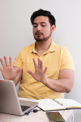 Student making the stop gesture front his laptop