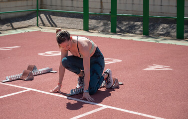 Female Athlete Preparing for Sprint in Starting Blocks