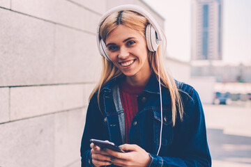 Half length portrait of happy young woman smiling at camera while choosing favourite songs in...