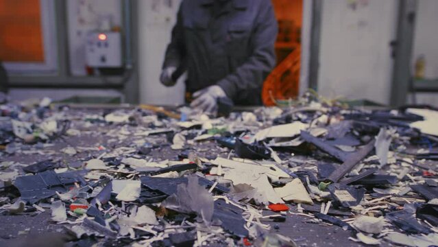 Worker looks for unsuitable for recycling items on conveyor belt churning out garbage slow motion. Employee hands move with precision swiftly separating unsuitable waste from recyclable materials