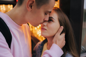 Naklejka premium A happy young couple in love, a boy and a girl, on a walk in the city, hugging and walking. Urban European love story and photo shoot