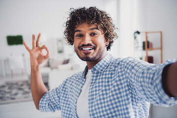 Photo of cool good mood man wear checkered shirt showing okey recording video vlog indoors house apartment room