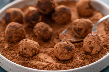 Artisanal chocolate truffles dusted with cocoa powder on a plate with a spoon