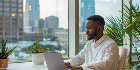 Plakat a Black entrepreneur working on a laptop in a minimalist office with a view of the city skyline