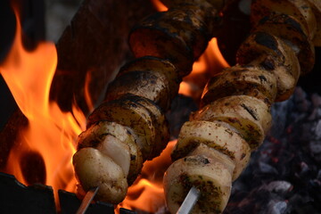 Potatoes with lard on skewers are fried over an open fire