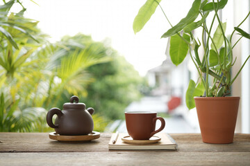 Tea cup and earthenware teapot at the balcony and notebooks side view