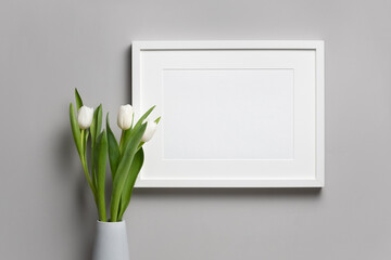 Blank landscape frame mockup with white fresh tulip flower in vase over grey wall background