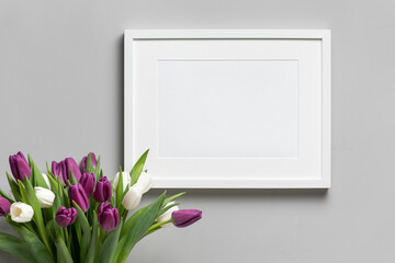 Landscape picture frame mockup with fresh tulips flowers in vase over grey wall background, copy...