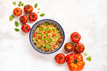 Tabbouleh o tabulè salad,  Arab dish from the Middle East and Mediterranean, with parsley, bulgur, onions, mint, tomatoes, seasoned with lemon juice, olive oil. White plate, top view