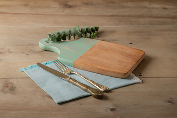 mock up decorative table setting of wooden kitchen cutting board with vintage cutlery on wooden...