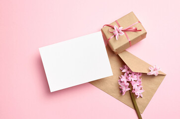 Blank greeting card mockup with envelope, gift box and pink flowers, card mock up with copy space