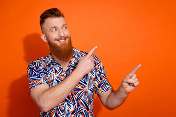 Photo of cheerful dreamy guy dressed print shirt looking showing two fingers emtpy space isolated orange color background