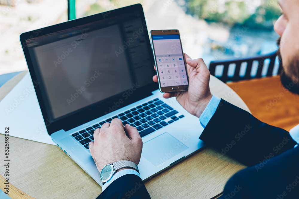 Poster cropped image of businessman dressed in formal wear making calculation on smarphone to checking fina