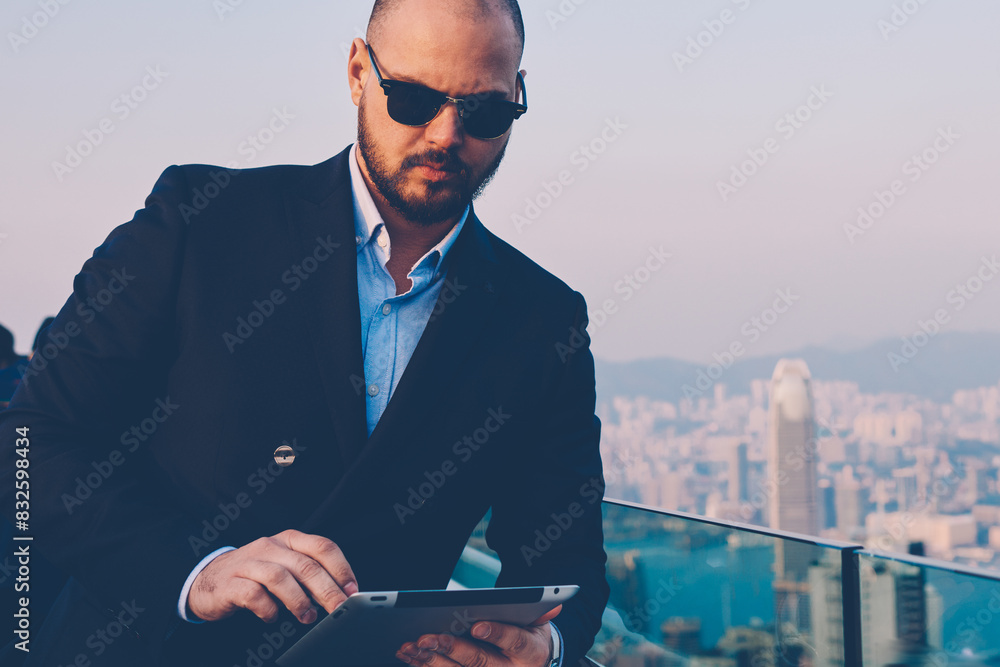 Poster confident executive manager in stylish sunglasses browsing internet website with financial news on d